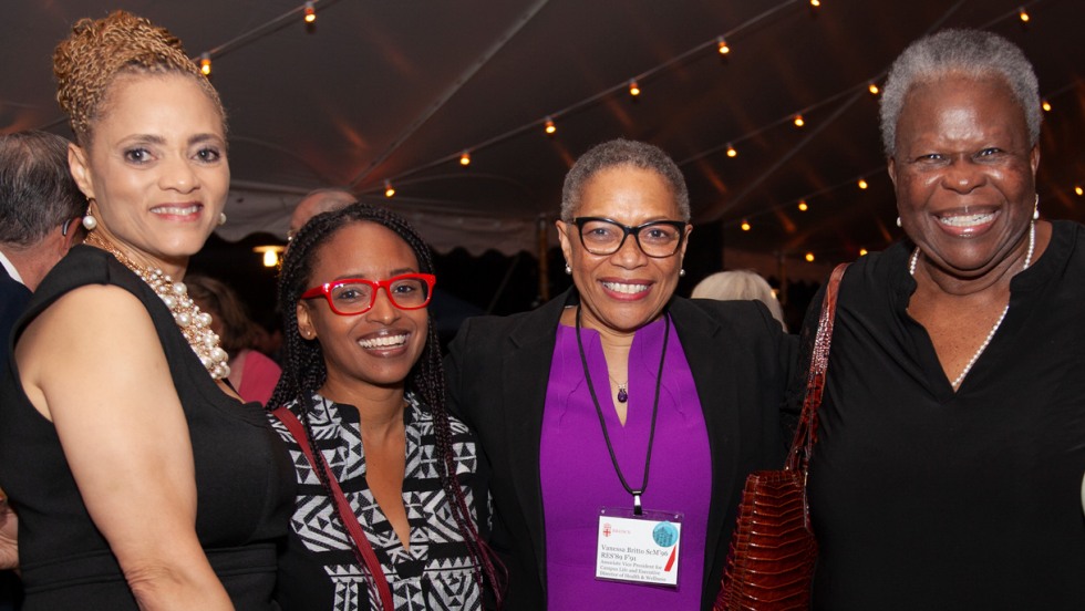 Four Medical School alumni embrace during a reception at the Grand Finale event