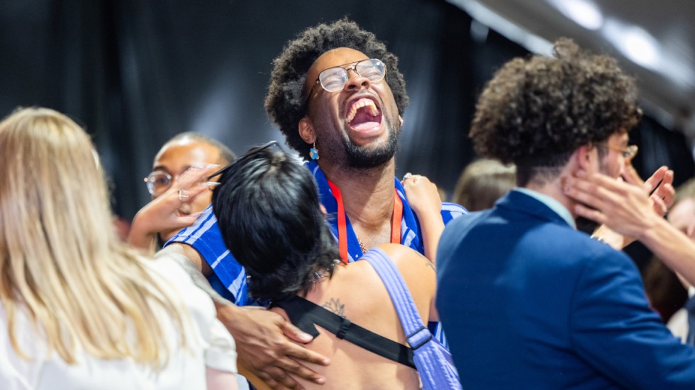 Two alumni laughing and hugging at a class event 